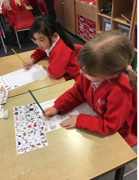 Children using a phonics strip to support writing.